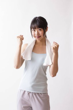 Boynunda havluyla yoga stüdyosunda poz veren Asyalı kadın.