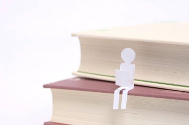 Beyaz arka planda izole edilmiş kağıt bir insan figürüne sahip kitap yığını
