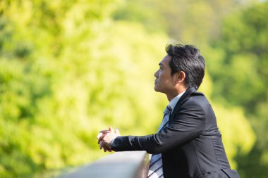 Düşünceli genç işadamının yan görünüşü parka bakıyor.