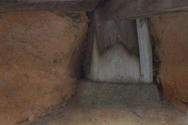 Yıpranmış ahşap kiriş toprak duvar yapısında dinleniyor.