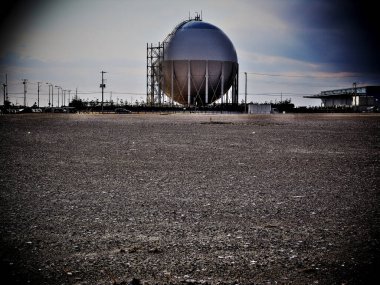 Çorak çakıl zeminde duran büyük küresel depolama tankı