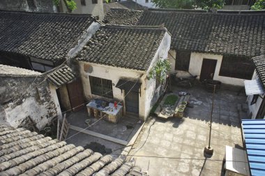 Güneşli geleneksel avluda eski fayanslı çatılar ve taş kaldırımlar var.