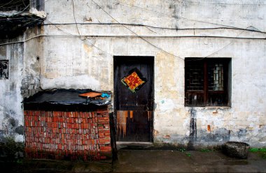 Eski ahşap kapı ve tek pencereli yıpranmış beton duvar