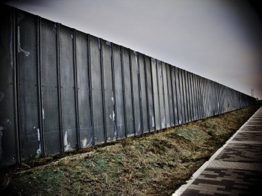 Boş arazi boyunca uzanan uzun metal duvar