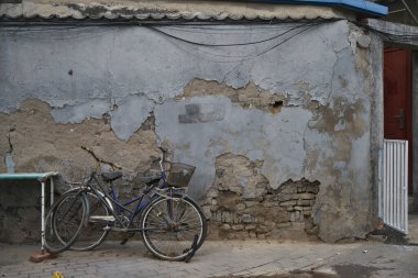 İki bisiklet yıpranmış duvara yaslanıyor.
