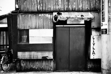 Kapalı metal kapılar ve soluk tentelerle donatılmış bir dükkan.