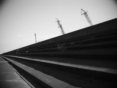 Açılı beton adımlar uzak inşaat vinçlerine doğru yükseliyor.