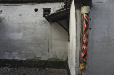 Yıpranmış duvarları ve berber direğiyle eski bir ara sokak.