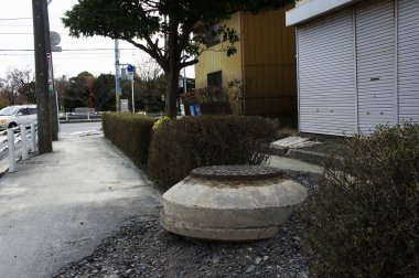 Kaldırımdaki çitin yanında beton rögar kapağı