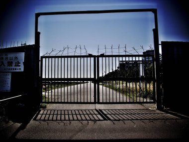 Kapalı metal kapı, yol girişinde gölgeler bırakıyor.