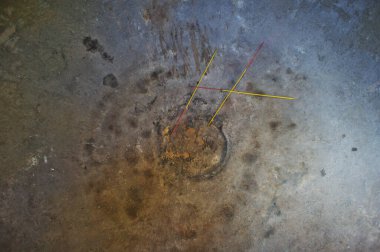 Yanmış tütsü çubukları eskimiş beton yüzeyde duruyor.