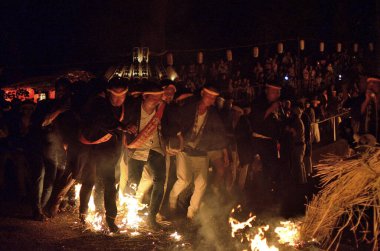 Geleneksel halk festivalinde ateşin yanındaki bir grup insanın gece görüşü      