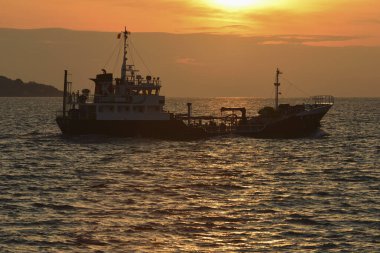 Denizde gün batımı ve doğada gemi.