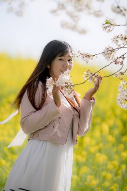 Parkta kiraz çiçekleri olan güzel Asyalı kadın.