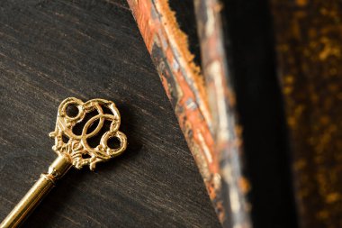 Altın zincirli antika anahtar. Koyu ahşap zemin üzerine kitaplar.