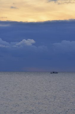 Denizde gün batımı ve doğa arka planında bir tekne