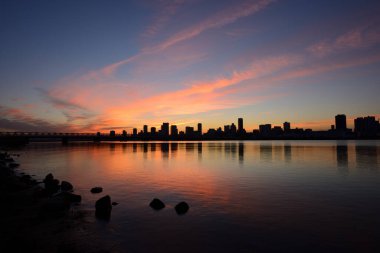 Şehrin üzerinde güzel bir günbatımı ufuk çizgisi ve sudaki yansıma   