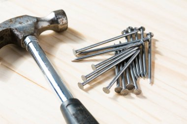 Tahta zemin üzerinde çiviler olan çekicin yakın plan görüntüsü