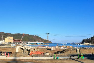 Açık mavi gökyüzünün altında, suyun yakınındaki inşaat alanı