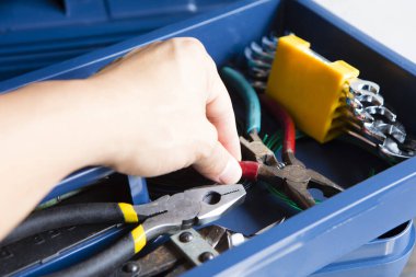 Bir adam kutunun tamiri için aletleri alıyor.