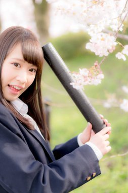 Okul üniformalı güzel bir Asyalı kız, bahar parkında poz veriyor.