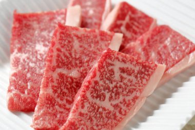 Yakın plan, tabaktaki çiğ et dilimlerini gösteriyor.