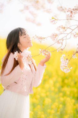 Parkta kiraz çiçekleri olan güzel Asyalı kadın.