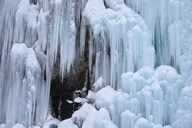 Şelalenin üzerindeki buz saçakları doğanın arka planında