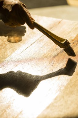 Erkek eli ahşap arka planda boya fırçası kullanıyor.