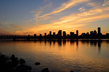 Şehrin üzerinde güzel bir günbatımı ufuk çizgisi ve sudaki yansıma   