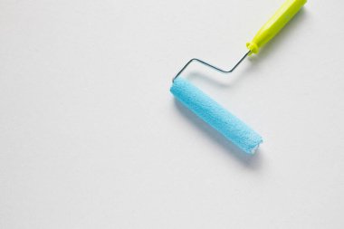 Beyaz arka planda mavi bir boya silindirinin yakın plan görüntüsü.