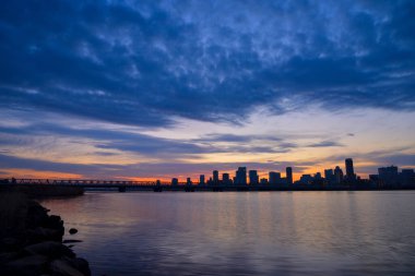 Şehrin üzerinde güzel bir günbatımı ufuk çizgisi ve sudaki yansıma   