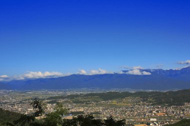 Dağlık vadideki kasabanın manzarası ve mavi gökyüzündeki bulutlar.