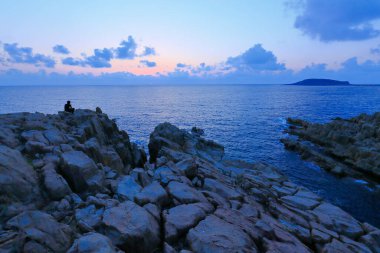 Kayaların üzerinde duran ve güzel günbatımının tadını çıkaran bir adam 