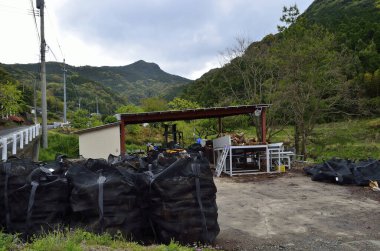 Yeşil orman dağlarının yakınındaki küçük kulübeyi çevreleyen siyah plastik torbalar.