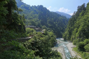 Dağ vadisinde güneşi yansıtan hızlı nehir.