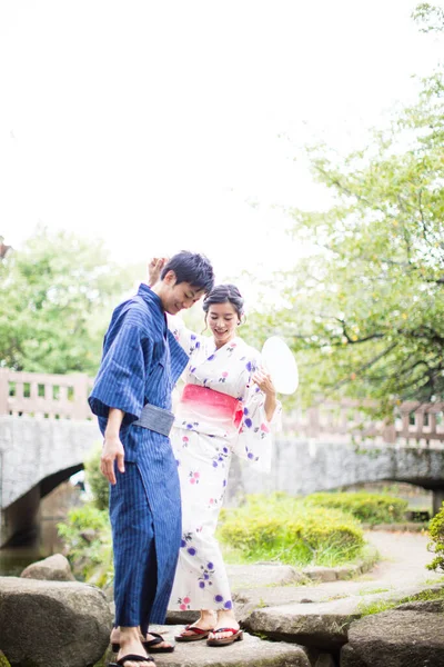 young Japanese couple wearing traditional kimono in summer park