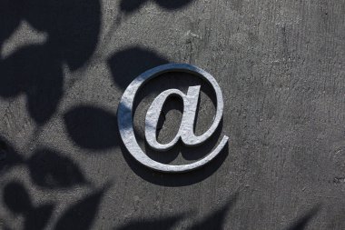 Gri duvar arkaplanındaki e- posta işareti.