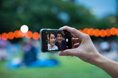 Geleneksel kimono giyen genç Japon çift parkta akıllı telefondan selfie çekiyor.