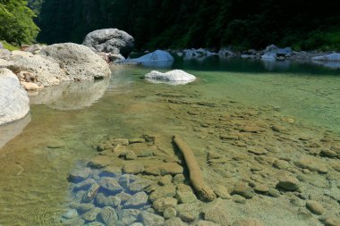 Dağ vadisinde güneşi yansıtan hızlı nehir.