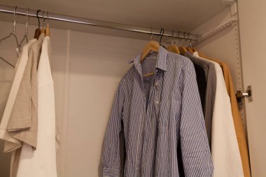 Korkuluklarda çeşitli gömleklerin asılı olduğu bir dolap.
