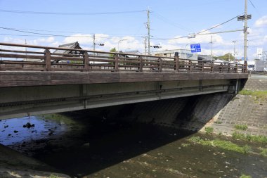 Mavi gökyüzünün altında küçük bir nehri geçen köprü
