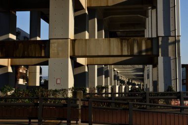 Yüksek yapıyı destekleyen beton sütunlar uzun gölgeler oluşturuyor.