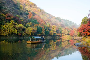 Nehirde renkli ağaçlar ve kayıkla sonbahar manzarası 