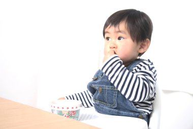 Küçük tatlı Asyalı çocuk masada oturuyor ve evde yemek yiyor. 