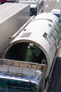 Kamyonlar arasında endüstriyel ekipman taşıyan büyük silindirik konteynır.