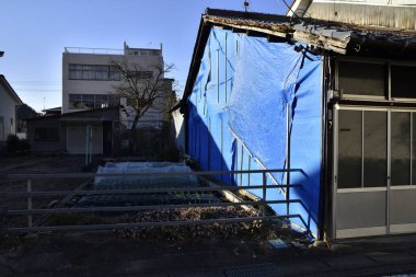 Etrafı çitlerle çevrili mavi muşamba bina.