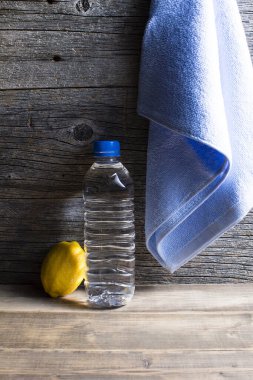 Sağlıklı bir yaşam tarzı. Ahşap zemin üzerinde bir şişe su, havlu ve limon.