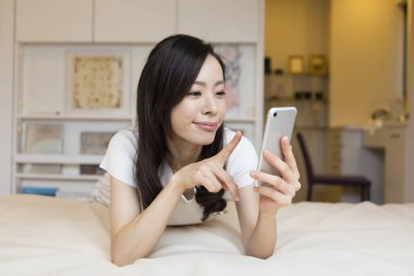 Genç ve güzel bir kadın telefonunu kullanıyor. 