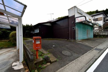 Boş yol ve kırmızı posta kutusunun yanındaki terk edilmiş bina.